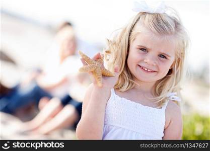 Adorable Little Blonde Girl with Starfish at The Beach.