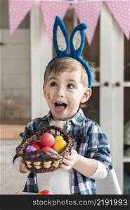 adorable little boy holding basket with easter eggs