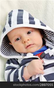 Adorable little boy in striped blouse on blanket