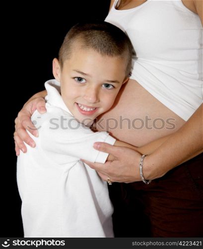 Adorable little boy listening to his mother&rsquo;s pregnant belly.