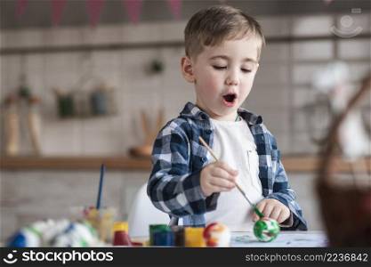 adorable little boy painting easter eggs