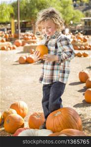 Adorable Little Boy Sitting and Holding His Pumpkin in a Rustic Ranch Setting at the Pumpkin Patch.. Adorable Little Boy Sitting and Holding His Pumpkin in a Rustic Ranch Setting at the Pumpkin Patch.