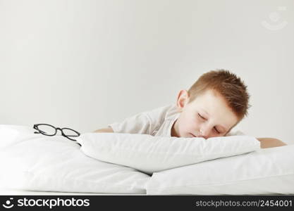 Adorable little boy sleeping in bed. morning dreaming on white bed. glasses from the side.. Adorable little boy sleeping in bed. morning dreaming on white bed. glasses from the side