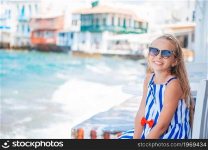 Adorable little girl at Little Venice the most popular tourist area on Mykonos island, Greece. Beautiful kid on Little Venice background.