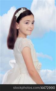 Adorable little girl dressed in communion with a blue sky of background