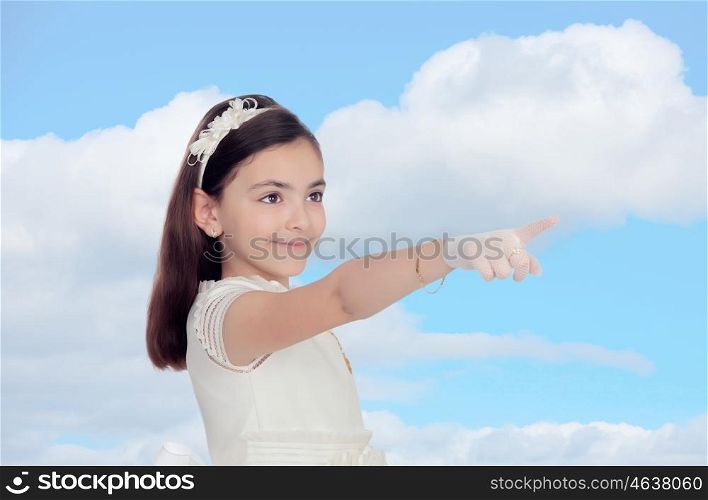 Adorable little girl dressed in communion with a blue sky of background