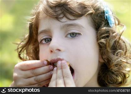 Adorable little girl eating chocolate outdoor field