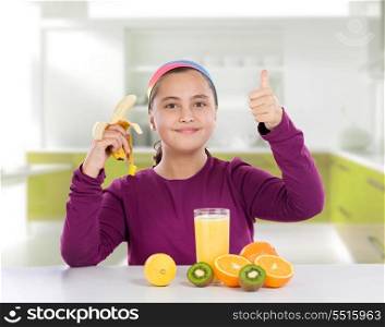Adorable little girl eating fruits saying Ok on the kitchen