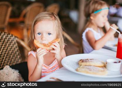 Adorable little girl having breakfast outdoors. Adorable little girl having breakfast at outdoor cafe