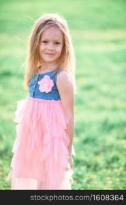 Adorable little girl in blooming apple garden on beautiful spring day. Portrait of beautiful kid in dress. Adorable little girl enjoying spring day in apple blooming garden