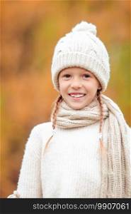 Adorable little girl in warm hat at beautiful autumn day outdoors. Portrait of adorable little kid with yellow leaves in fall. Autumn time