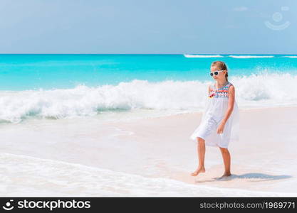 Adorable little girl on the pebble beach having fun. Cute little girl at beach during summer vacation