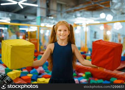 Adorable little girl playing with soft cubes, playground in entertainment center. Play area indoors, playroom