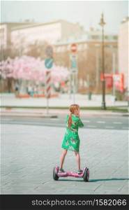 Adorable little girl riding on a electric scooter . Personal eco transport, gyroscooter, smart balance wheel. Popular modern transport. Happy kid using popular electric transport a self-balancing, gyro scooter