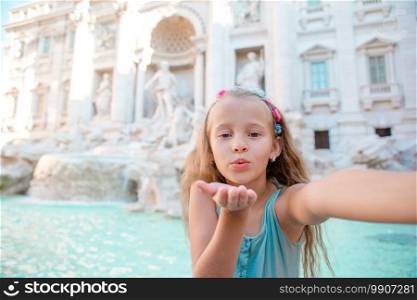 Adorable little girl taking selfie by the Fountain of Trevi in Rome. Happy kid enjoy her european vacation in Italy. Adorable little girl taking selfie by the Fountain of Trevi in Rome.