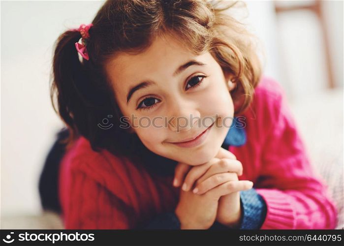 Adorable little girl with sweet smile lying down on bed. Close-up potrait.