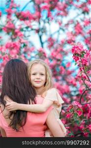 Adorable little girl with young mother in blooming cherry garden on beautiful spring day. Adorable little girl with young mother in blooming cherry garden on spring day