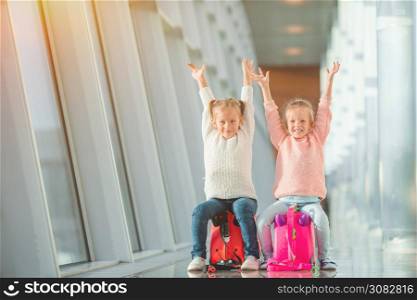 Adorable little girls at airport in big international airport near window. Adorable little girls in airport with her luggage waiting for boarding