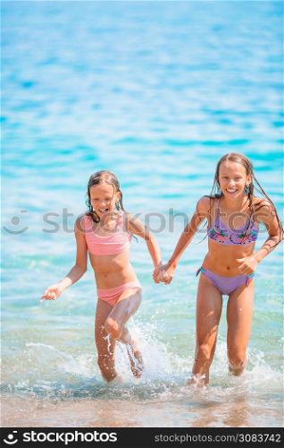 Adorable little girls having fun on the beach in shallow water. Adorable little girls having fun on the beach