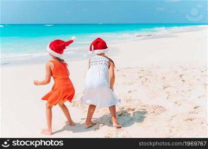 Adorable little girls in Santa Hats with starfish on white empty beach. . Adorable little girls with starfish on white empty beach