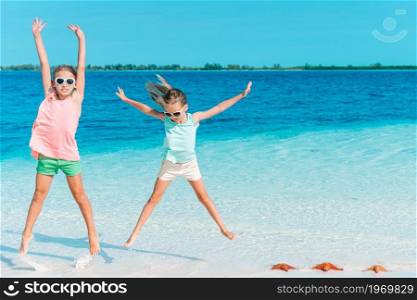 Adorable little girls on the beach during summer vacation with turquoise ocean and white sand. Adorable little girls have a lot of fun on the beach.