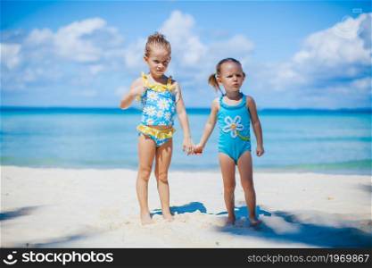Adorable little girls on the beach during summer vacation with turquoise ocean and white sand. Adorable little girls have a lot of fun on the beach