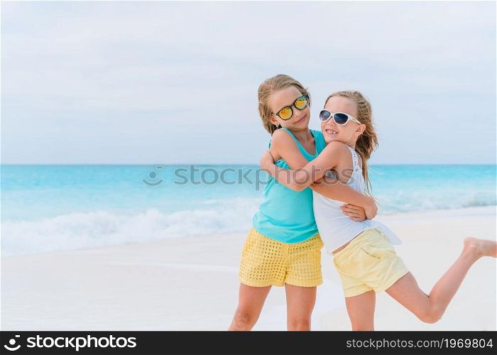 Adorable little kids on the beach during summer vacation with air mattress. Little girls having fun at tropical beach during summer vacation playing together