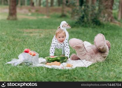 Adorable little toddler girl with a big teddy bear having fun in the summer park on sunny day. concept of summer holiday picnic. selective focus. Adorable little toddler girl with a big teddy bear having fun in the summer park on sunny day. concept of summer holiday picnic. selective focus.