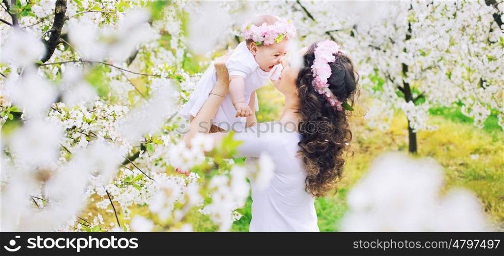 Adorable mother and her little kid resting in a spring orchard