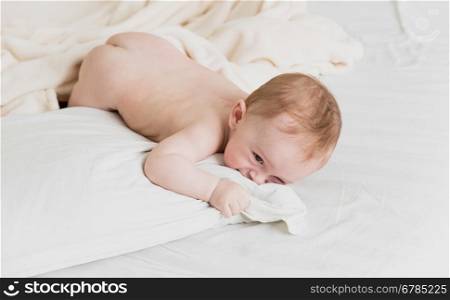 Adorable naked baby boy lying on in big white pillow