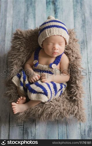 Adorable newborn baby sleeping in cozy room. Cute happy infant baby portrait with sleepy face in bed. Soft focus at the baby eyes. Newborn nursery care concept.