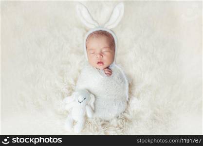 Adorable newborn baby sleeping in cozy room. Cute happy infant baby portrait with sleepy face in bed. Soft focus at the baby eyes. Newborn nursery care and baby lullaby concept.