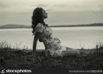 Adorable pregnant woman lying on the fresh grass