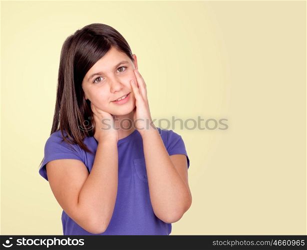 Adorable preteen girl touching her face isolated on a yellow background