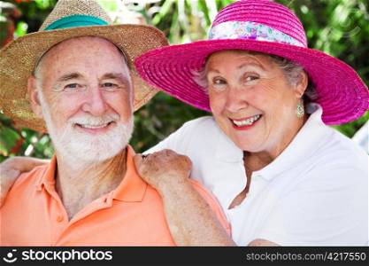 Adorable senior couple smiling in their straw hats.