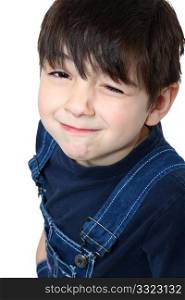 Adorable six year old caucasian boy in overalls winking at camera.