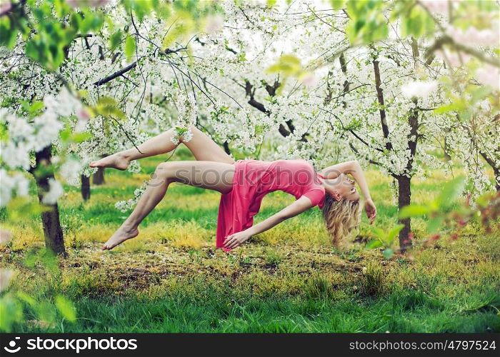 Adorable slim lady levitating in the colorful orchard