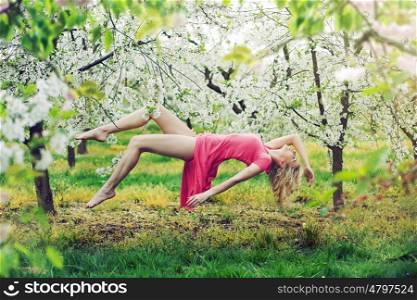Adorable slim lady levitating in the colorful orchard