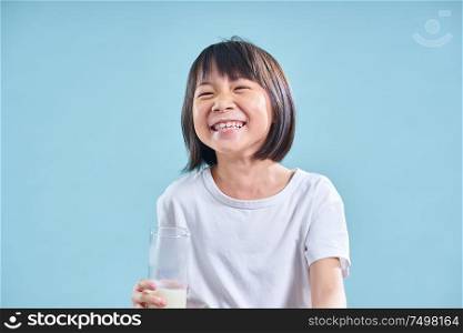 Adorable smart asian little girl happy with drinking milk on blue background