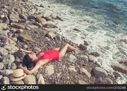 Adorable sporty girl in a bikini on the summer beach. Stunning tanned girl takes a sunny bath on the beach.