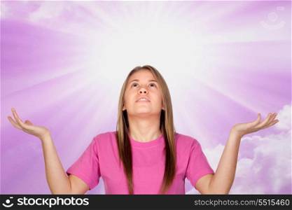 Adorable teen girl praying with a lighted sky