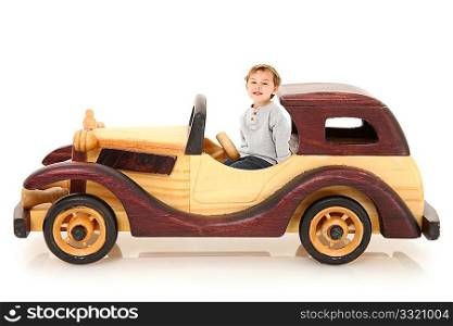 Adorable three year old american boy sitting in wooden toy car over white background with reflection. Natural and stained wood.