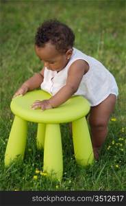 Adorable toddler playing with a chair in the garden