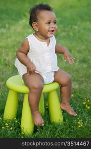 Adorable toddler playing with a chair in the garden