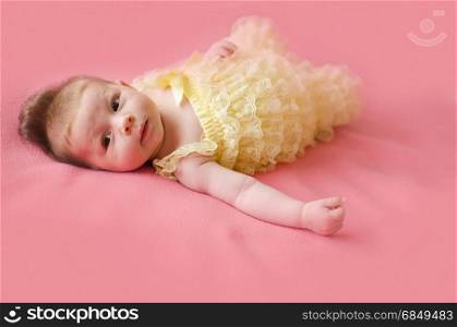 adorable two months old baby girl lying on her back on a pink blanket