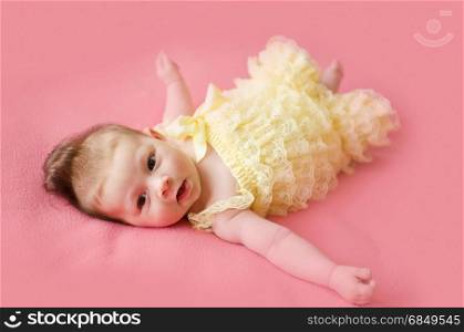 adorable two months old baby girl lying on her back on a pink blanket