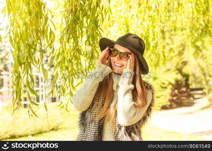 Adorable woman in sunglasses. Beauty and fashion of women. Young attractive fashionable girl wearing stylish hat waistcoat and sunglasses. Pretty woman around leaves of willow tree.