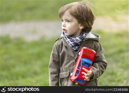 adorable young boy with toy car looking away