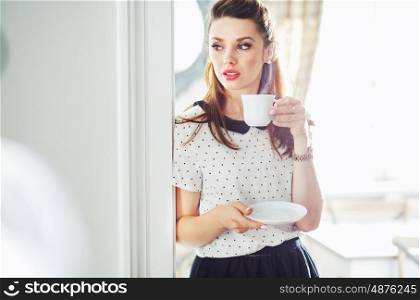 Adorable young woman drinking tasty coffee