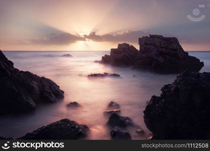 Adraga beach at amazing colors sunrise. Long exposure shot of rocky coastline, Portugal.